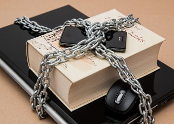 Phone, book and laptop locked under chains as a visual representation of cyber security
